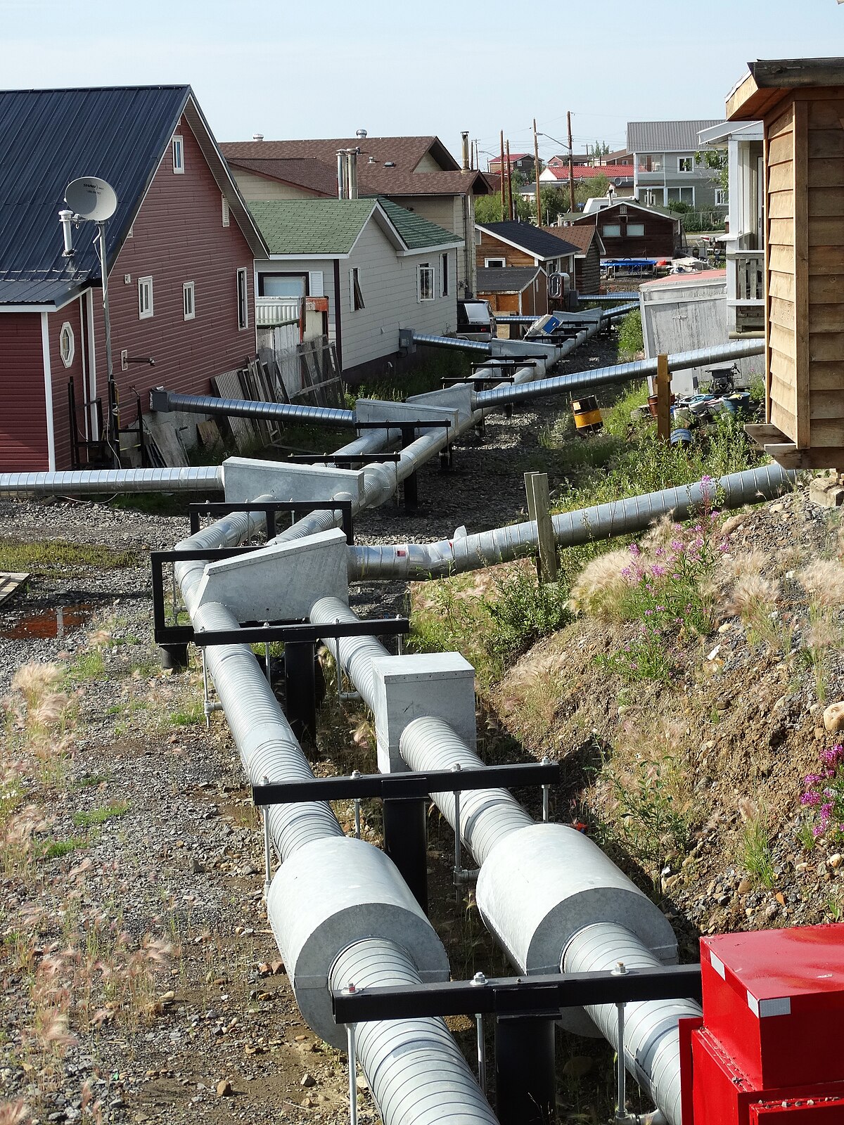 Above-ground heating and water utilidors in Inuvik, NWT — northern infrastructure adapted to permafrost, signalling the high cost of energy delivery in remote northern communities